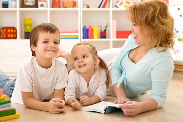 Дети веселятся, читая истории со своей мамой — стоковое фото