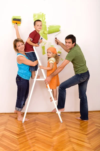 Famille heureuse avec des ustensiles de peinture repeignant leur maison — Photo