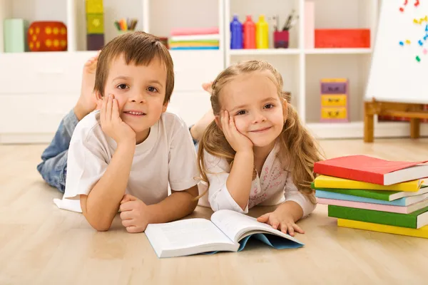 Happy kids with books laying on the floor Stock Image