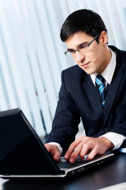 Successful happy smiling businessman working with laptop at offi clipart