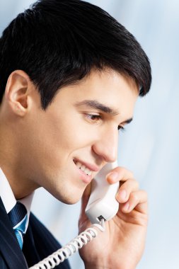 Successful businessman with phone at office clipart