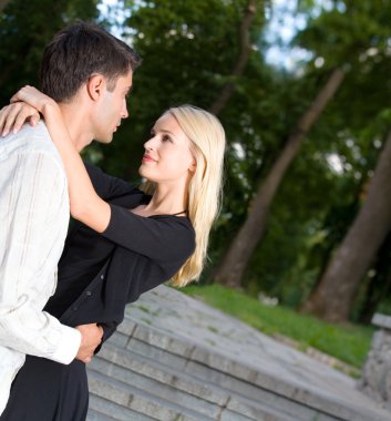 Young happy embracing couple walking together outdoors clipart