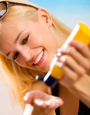 Young beautiful smiling woman with sun-protection cream on beach clipart