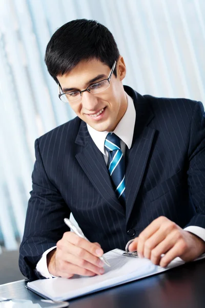 Portret van lachende zakenman schrijven werken op kantoor — Stockfoto