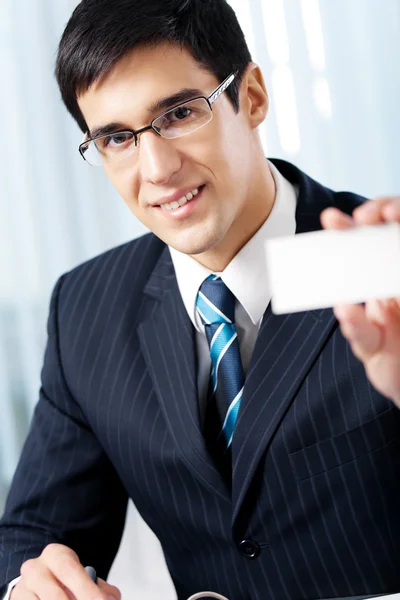 Улыбающийся бизнесмен, дающий визитку, в офисе — стоковое фото