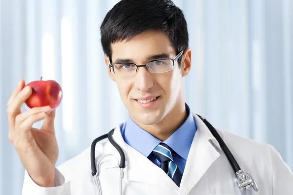 Médico sorridente feliz com maçã, no escritório — Fotografia de Stock