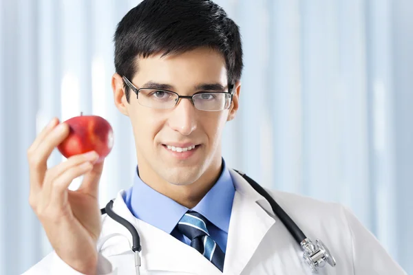 Médico sorridente feliz com maçã, no escritório — Fotografia de Stock