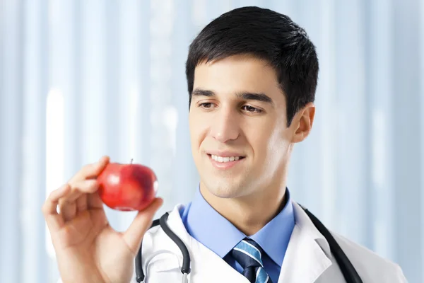Glada leende läkare med apple, på kontor — Stockfoto