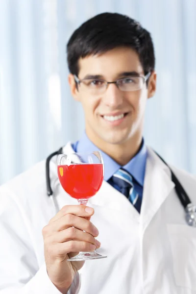 Joyeux médecin souriant avec du vin rouge, au bureau — Photo