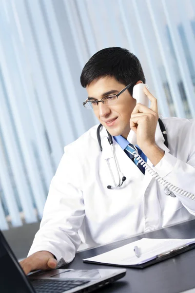 Médico de sucesso com telefone e laptop, no escritório — Fotografia de Stock