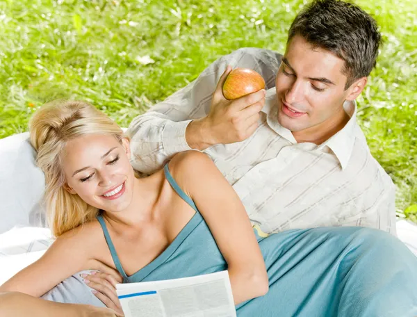Unga lyckliga paret tillsammans läsa tidningen utomhus — Stockfoto