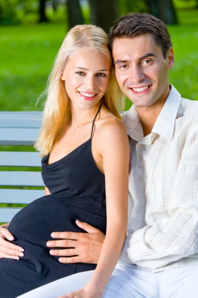 Счастливая красивая беременная женщина и ее муж, на улице — стоковое фото