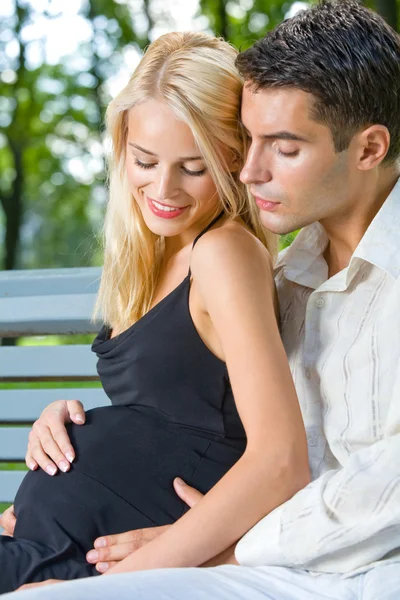 Счастливая красивая беременная женщина и ее муж, на улице — стоковое фото