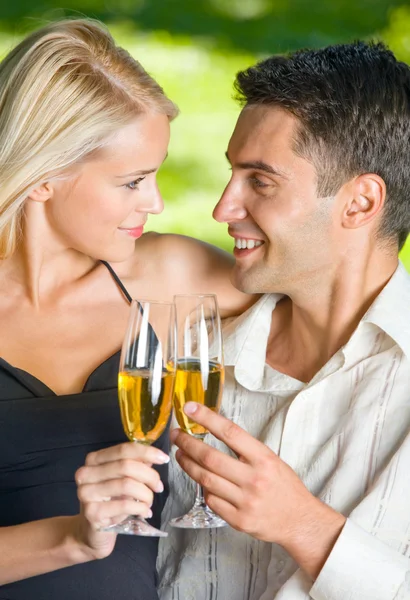 Młoda szczęśliwa para obchodzi z szampanem, na zewnątrz — Zdjęcie stockowe