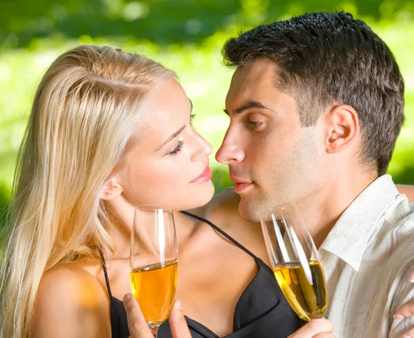 Молодая счастливая пара празднует с шампанским, на открытом воздухе — стоковое фото