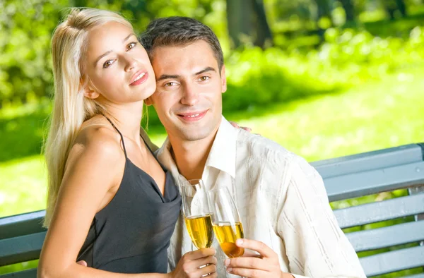Jovem casal feliz comemorando com champanhe, ao ar livre — Fotografia de Stock