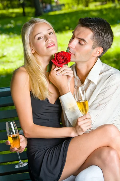 Młoda szczęśliwa para z Szampanii, dar i rose, na zewnątrz — Zdjęcie stockowe