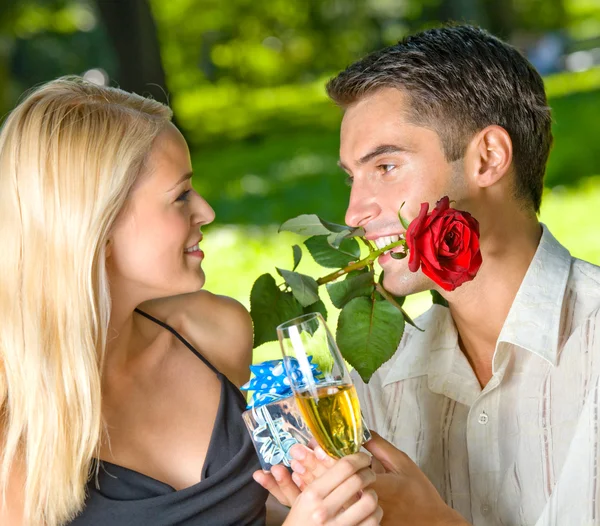 Смішна молода щаслива пара з подарунком і трояндою, на відкритому повітрі — стокове фото
