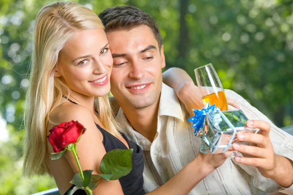 Grappige jonge gelukkige paar met cadeau en rosa, buitenshuis — Stockfoto