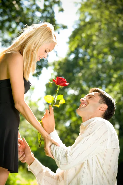 Смешная молодая счастливая пара с розой, на открытом воздухе — стоковое фото