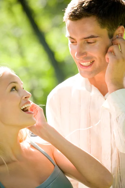 Glückliches junges Paar hört gemeinsam Musik im Headset, im Freien — Stockfoto