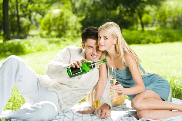 Jovem casal feliz comemorando com champanhe no piquenique — Fotografia de Stock