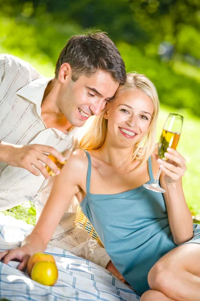 Молодая счастливая пара празднует с шампанским на пикнике — стоковое фото