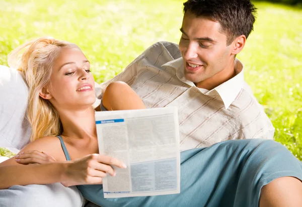 Glücklich lächelndes junges Paar beim gemeinsamen Lesen im Freien — Stockfoto