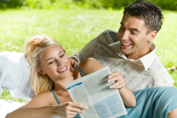 年轻快乐的夫妻在一起读报纸户外 — 图库照片