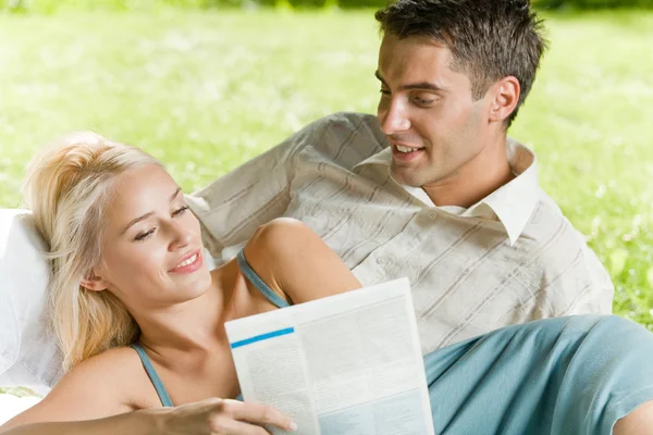 Unga lyckliga paret tillsammans läsa tidningen utomhus — Stockfoto