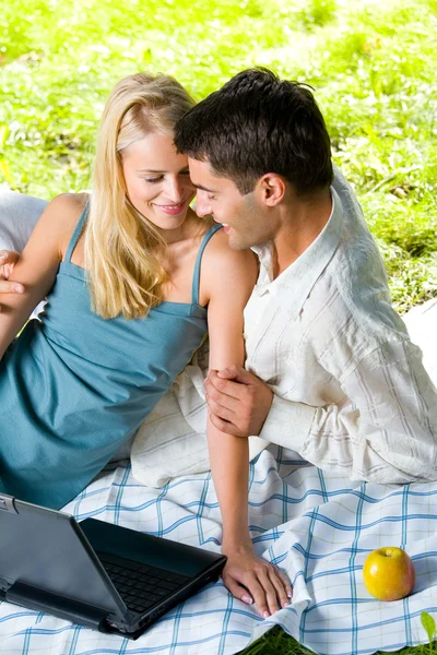 Jovem feliz casal sorridente com laptop no piquenique — Fotografia de Stock