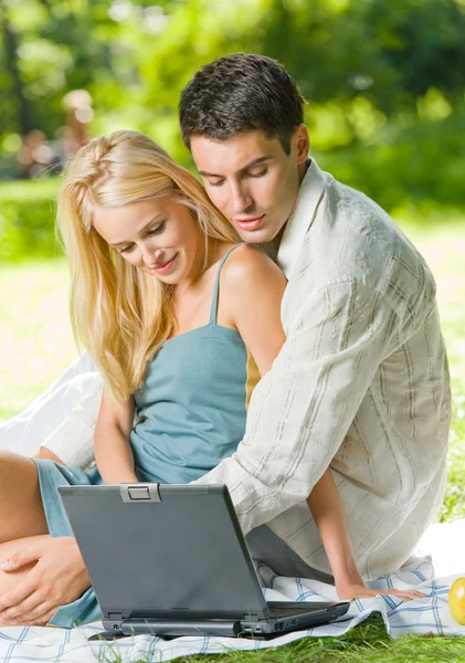 Молодая счастливая пара, используя ноутбук вместе, на открытом воздухе — стоковое фото