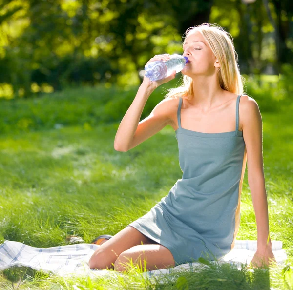 Ung kvinna med en flaska vatten utomhus — Stockfoto