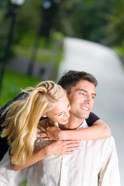 Молодая счастливая улыбка обнимающая пара, идущая вместе на улице — стоковое фото