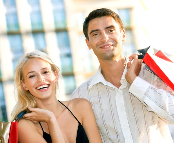 Young attractive happy couple with shopping bags outdoors — Stock Photo, Image