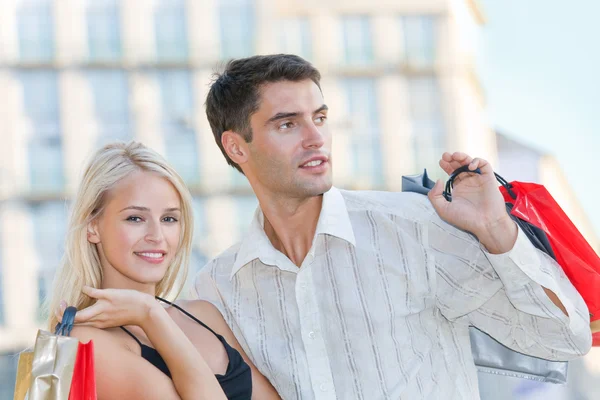 Unga attraktiva glad amorösa par med påsar utomhus — Stockfoto