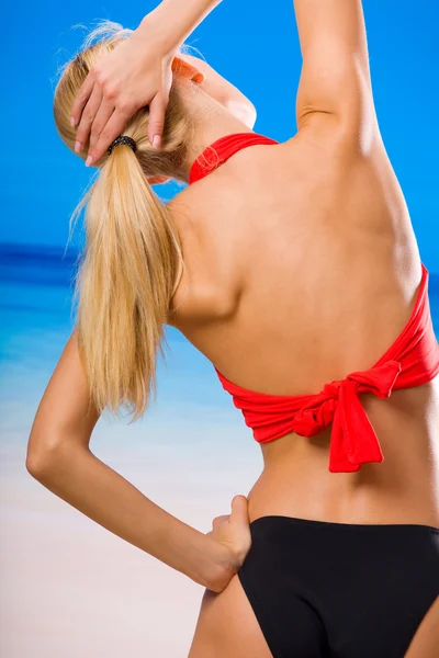 Молодая женщина в спортивной одежде делает упражнения на морском пляже — стоковое фото