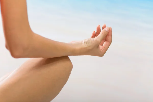 Jovem fazendo movimentos de ioga ou meditando na praia — Fotografia de Stock
