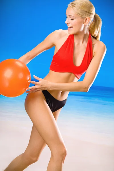 Молодая красивая женщина играет с мячом на пляже — стоковое фото