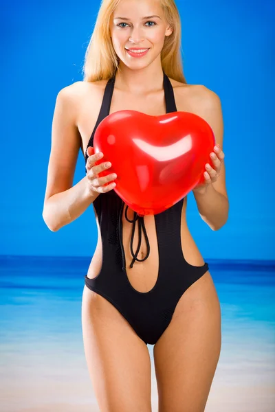 Joven hermosa mujer en bikini con globo de San Valentín en la playa — Foto de Stock