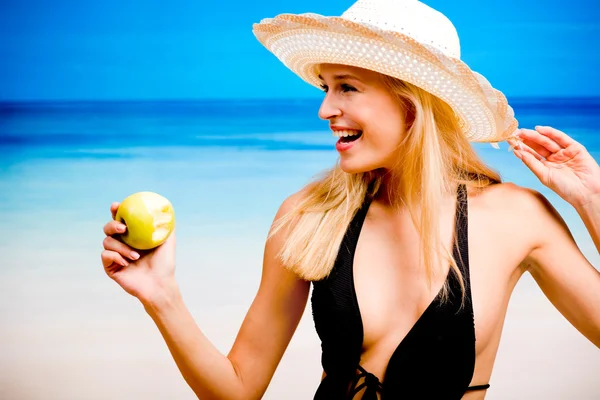 Unga leende kvinna med apple på stranden — Stockfoto