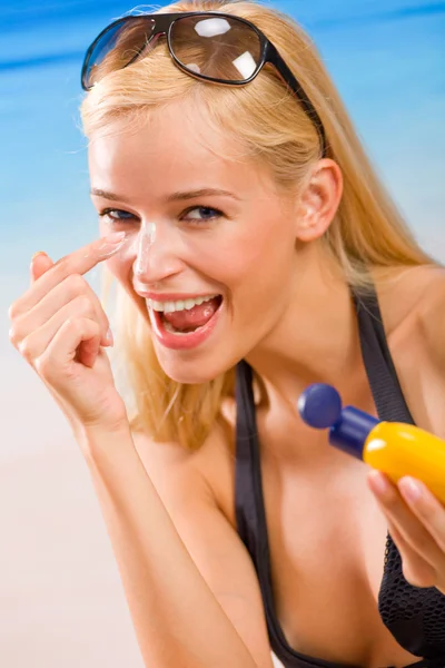 Young happy smiling woman with sun-protection cream on beach. Fo — Stock Photo, Image