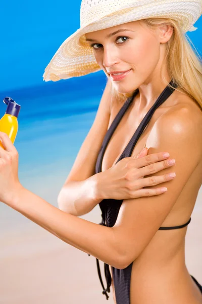 ビーチで太陽の保護クリームを持つ若い幸せな笑顔の女性 — ストック写真