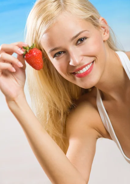 Unga glada leende kvinna med jordgubbe på stranden — Stockfoto