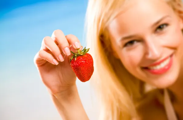 Young beautiful smiling blond woman with strawberry on sea beach — Stock Photo, Image