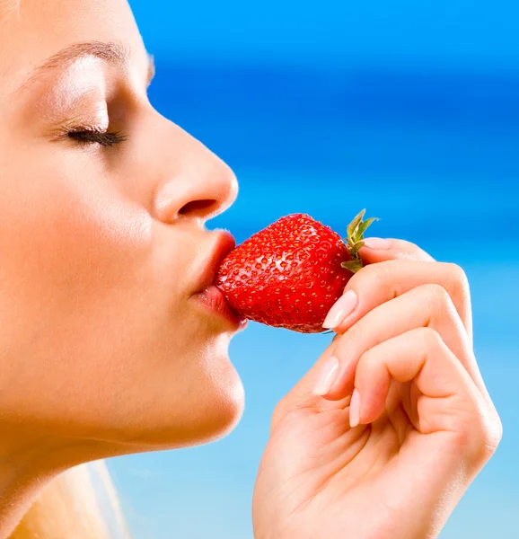 Portrait of beautiful young woman eating strawberry outdoors — Stock Photo, Image