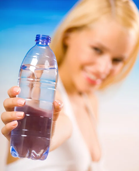 Mujer joven con botella de agua en bikini en la playa — Foto de Stock