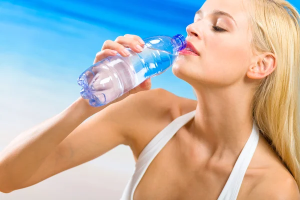 Jovem mulher bonita com garrafa de água na praia — Fotografia de Stock