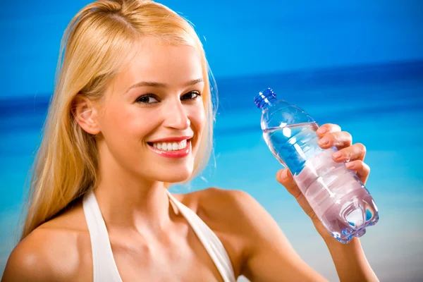 Женщина с бутылкой воды в купальниках на пляже — стоковое фото