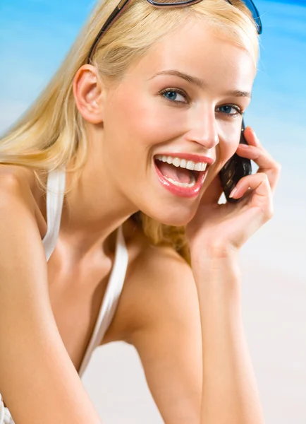 Joven mujer sonriente feliz en bikini con teléfono celular en la playa —  Fotos de Stock